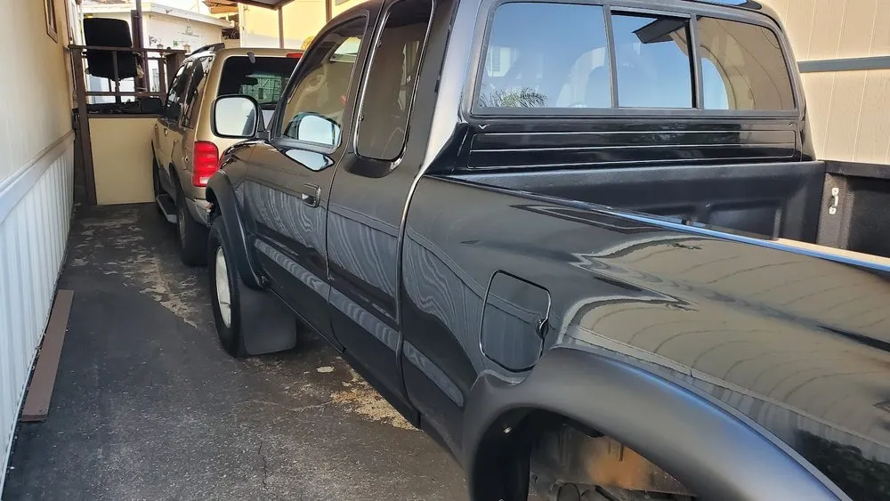 Black pickup truck seen from the rear quarter after its side collision damage was repaired